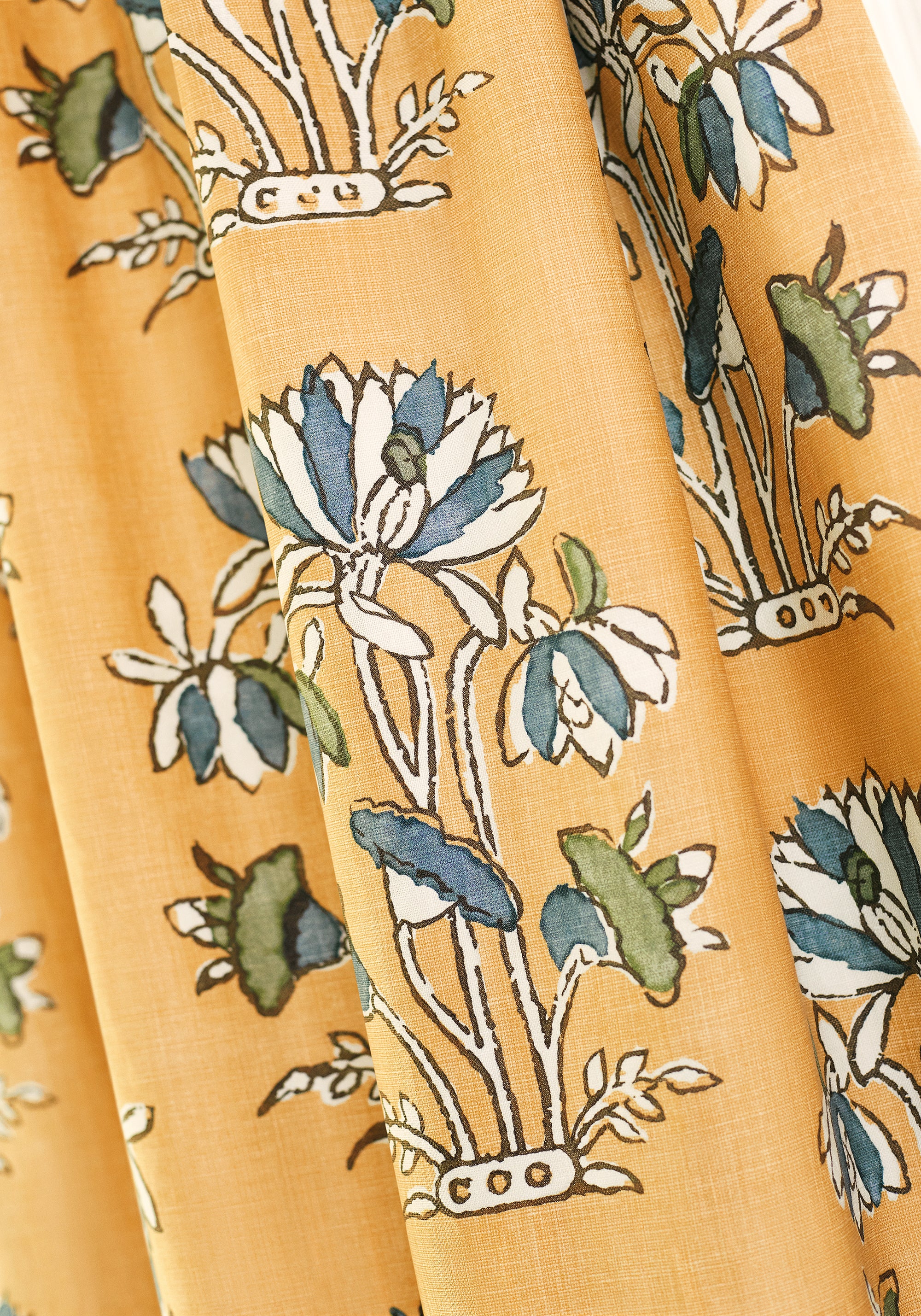 Detailed view of draperies in Lily Flower printed fabric in harvest gold color variant by Thibaut in the Mesa collection - pattern number F913202