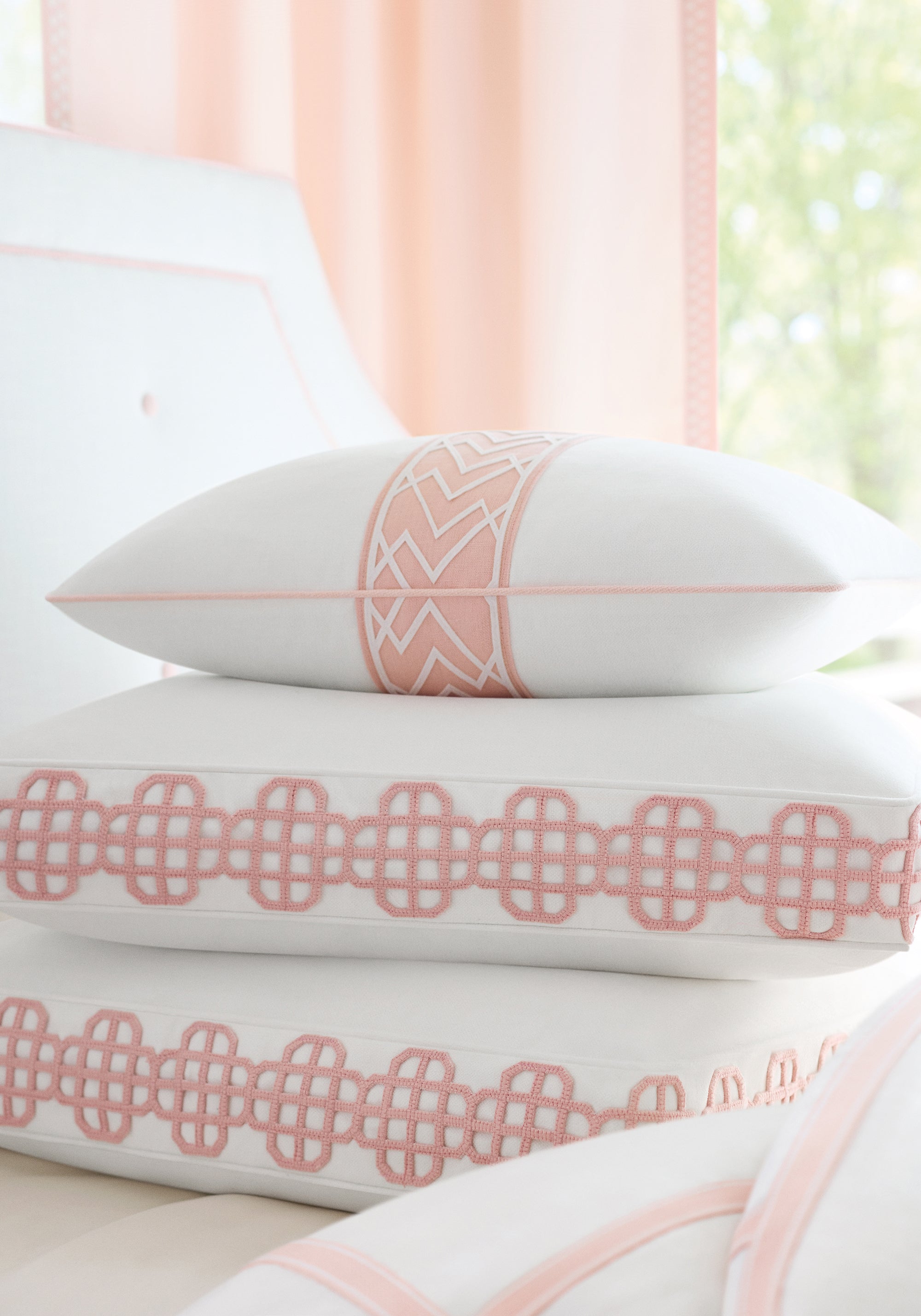 Pillows upholstered with Snow White Skye Linen wide woven fabric and blossom-colored trim tape of the Palisades collection by Thibaut - pattern number FWW7602