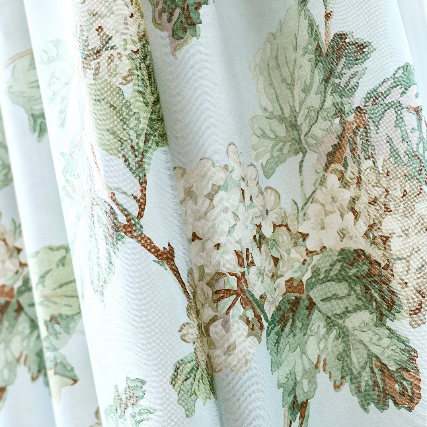 Detailed view of draperies in Sussex Hydrangea printed fabric in soft blue color variant by Anna French in the Bristol collection - pattern number AF57845