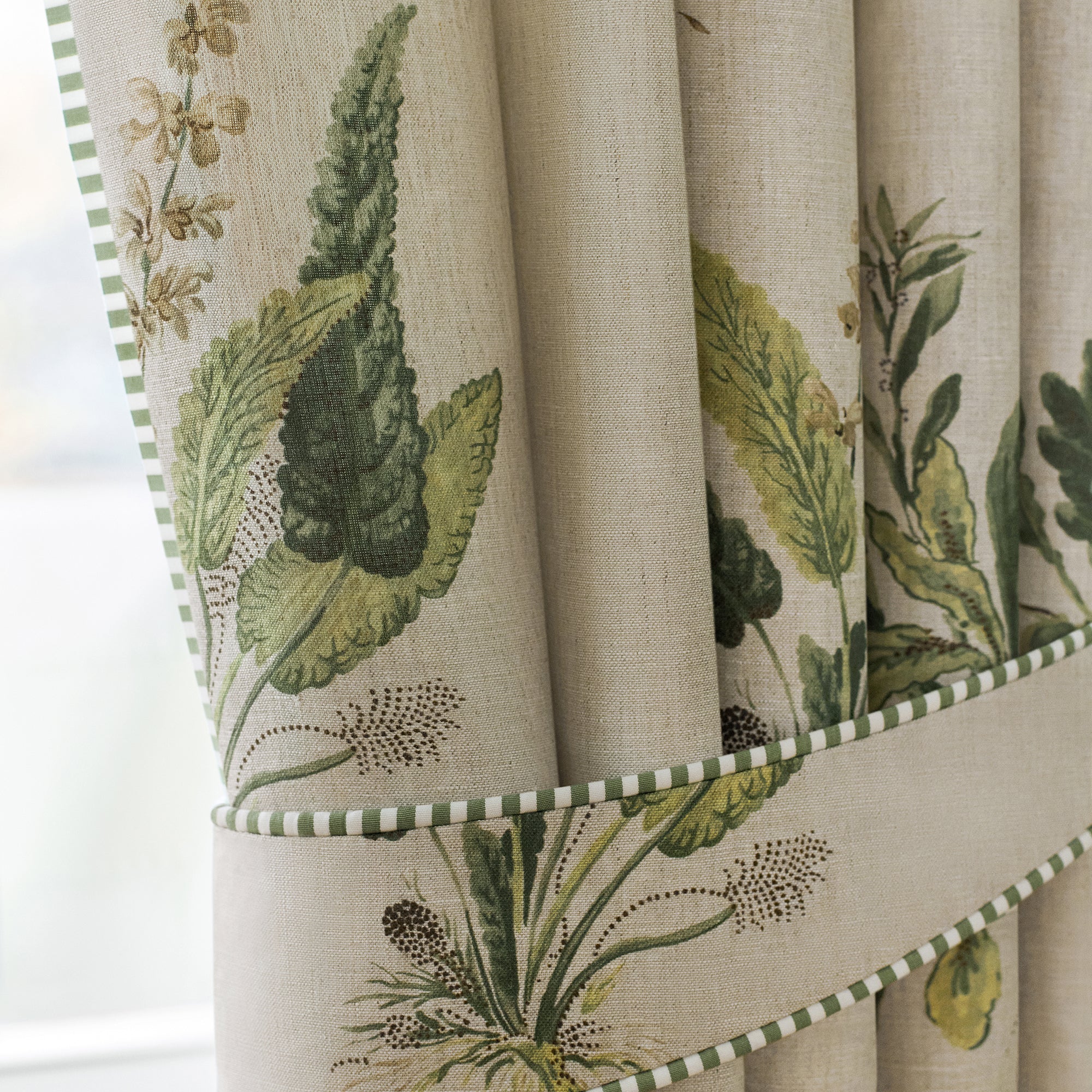 Detailed view of draperies in Woodland printed fabric in green on natural color variant by Anna French in the Bristol collection - pattern number AF57853
