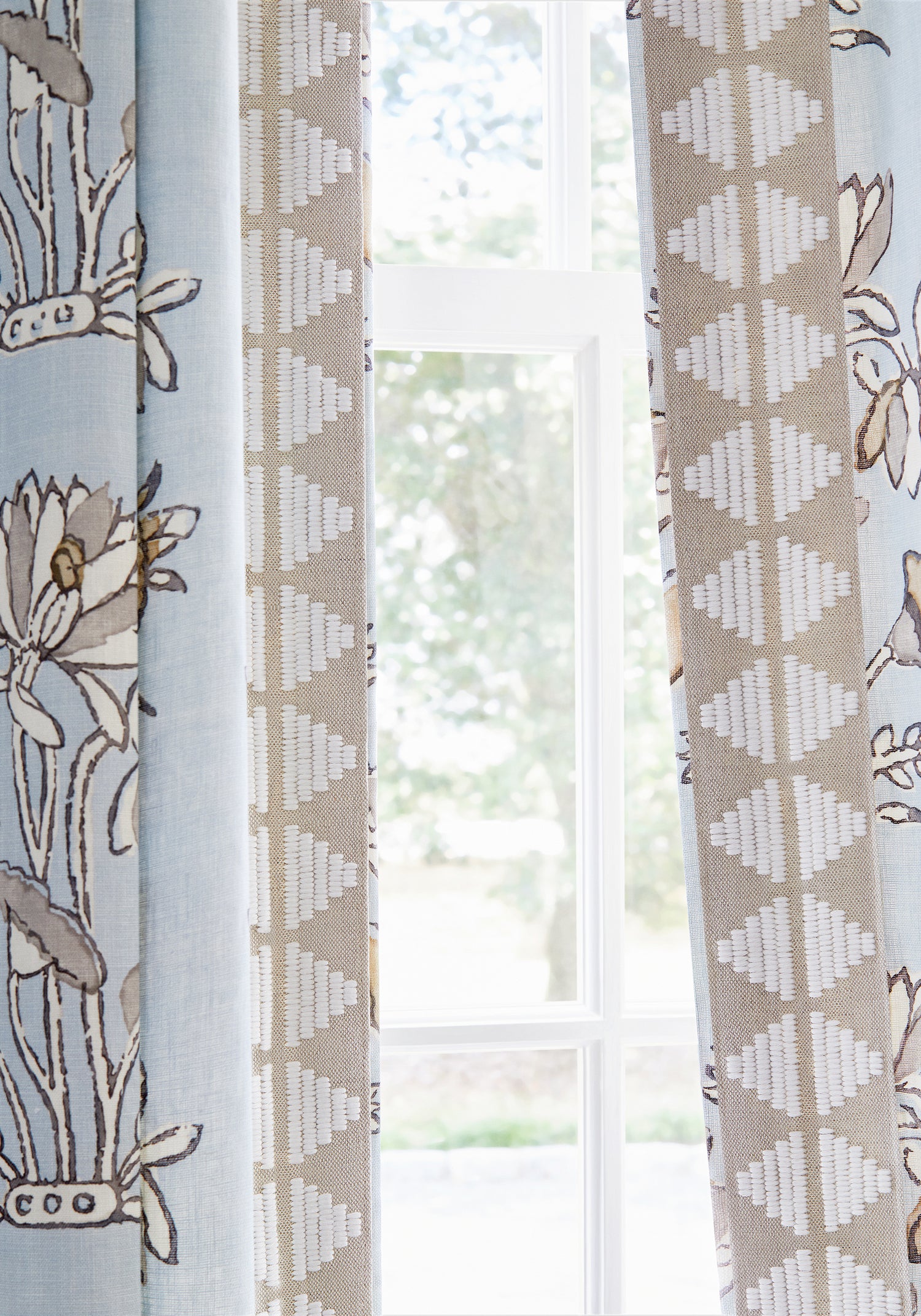 Detail of draperies in Lily Flower printed fabric in spa blue color with linen trim - pattern number F913201 - by Thibaut in the Mesa collection