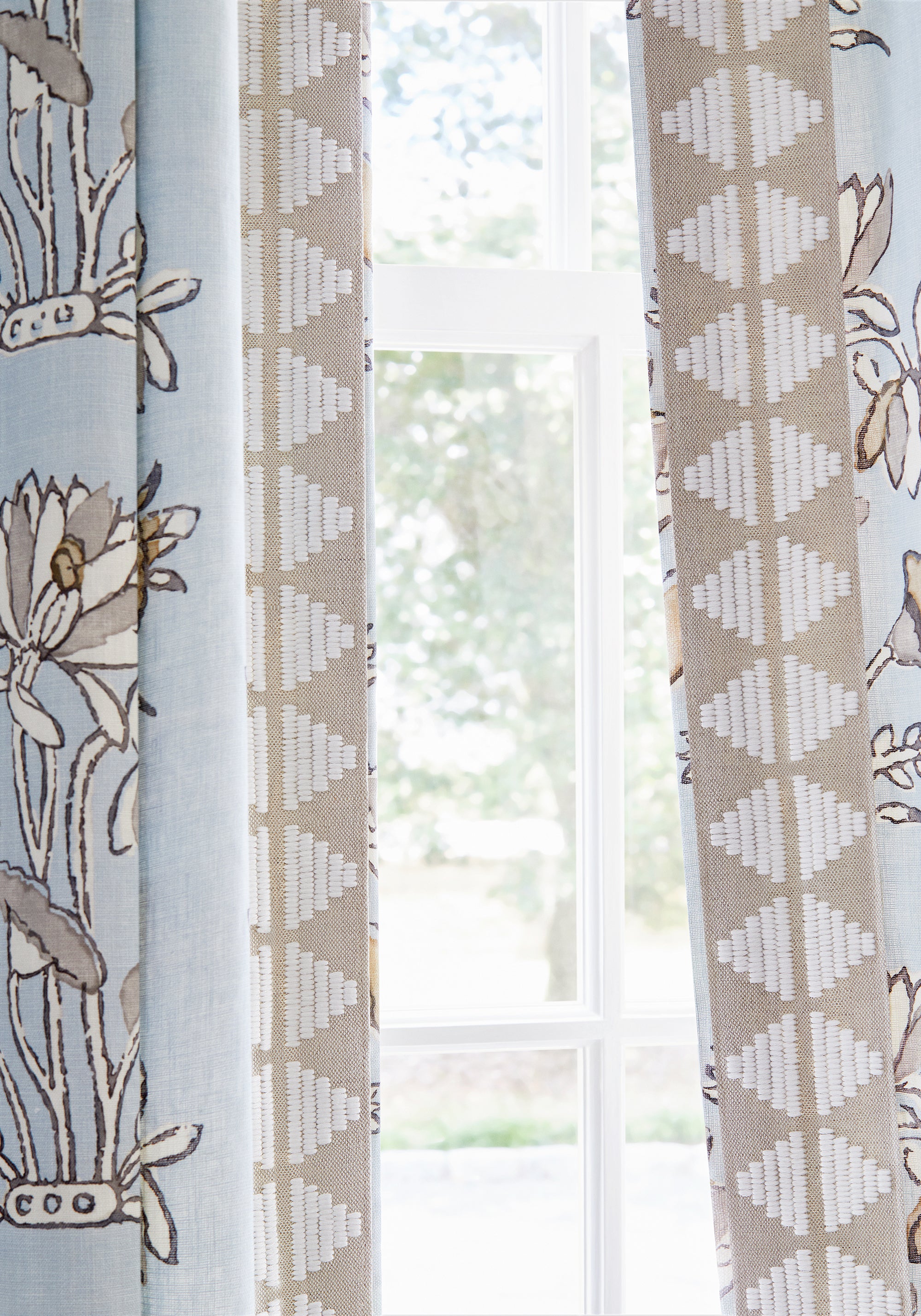 Detail of draperies in Lily Flower printed fabric in spa blue color with linen trim - pattern number F913201 - by Thibaut in the Mesa collection